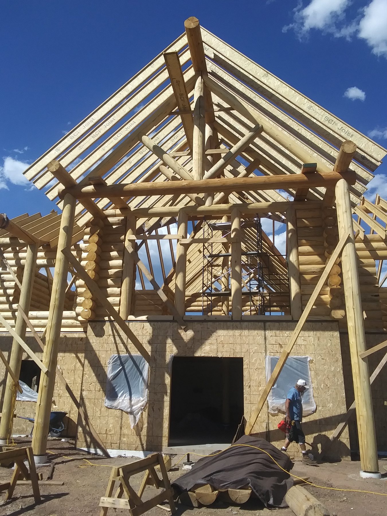 The gable end framed, seen from the ground with the crew working above.